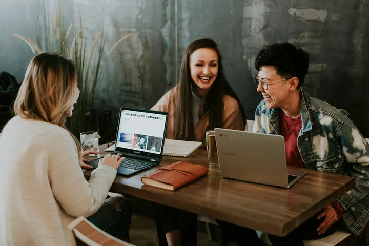 Equipo de trabajo conversando frente a laptops en una mesa