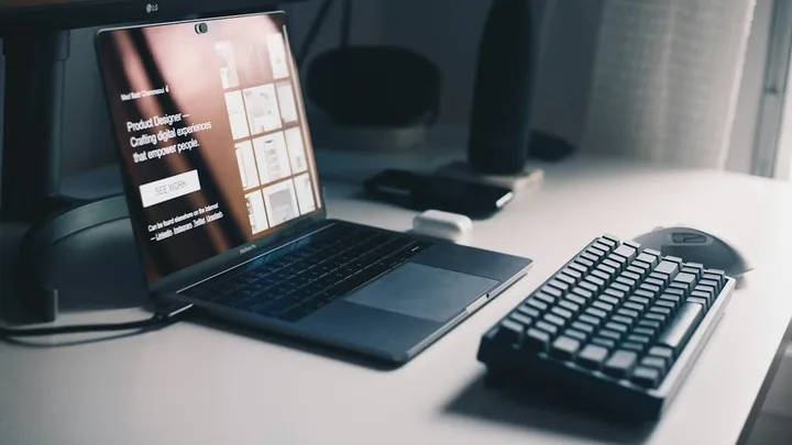 Teclado negro junto a una laptop sobre un escritorio